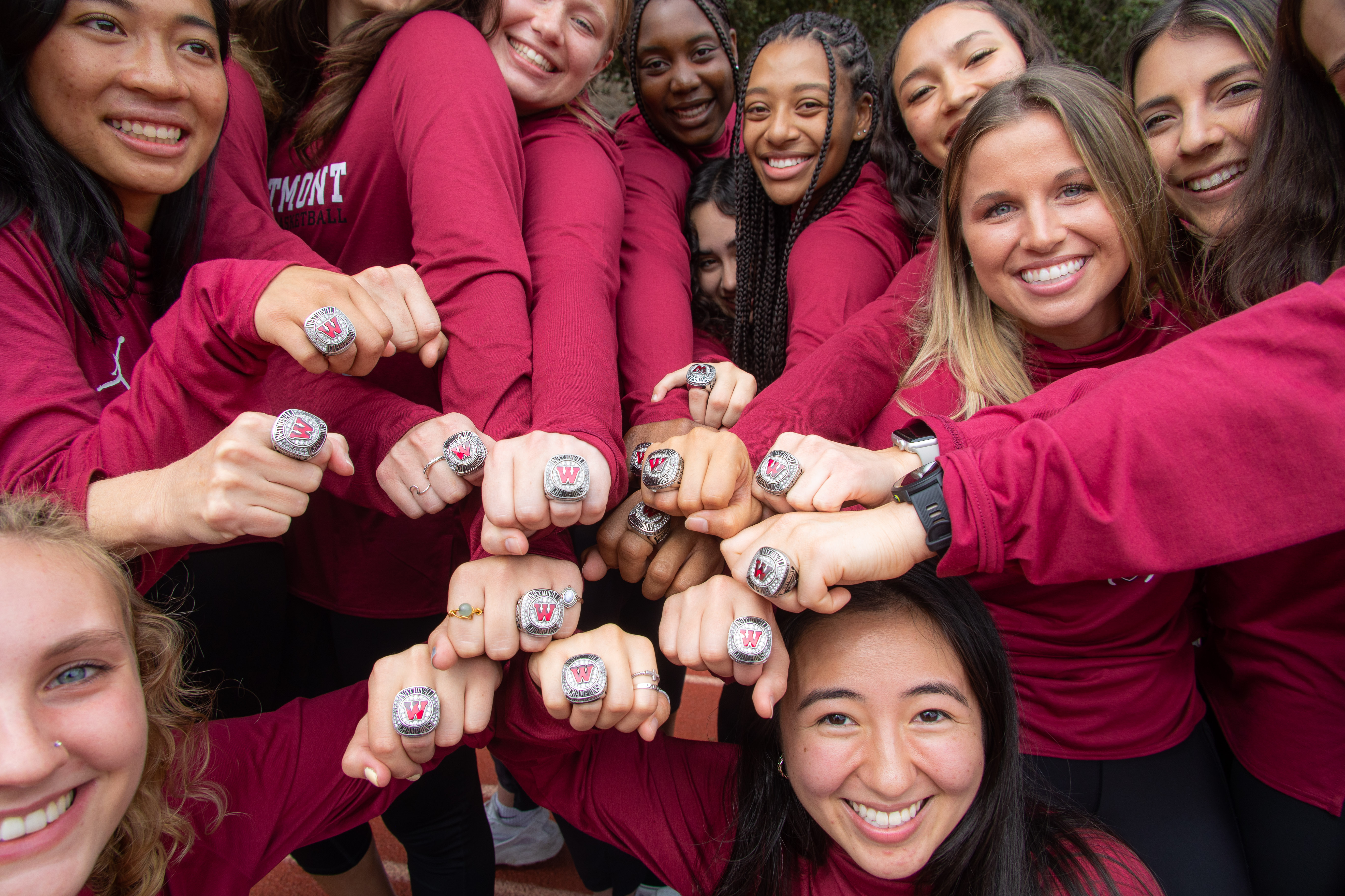 Women's basketball team displaying NAIA National Championship 2021 rings.